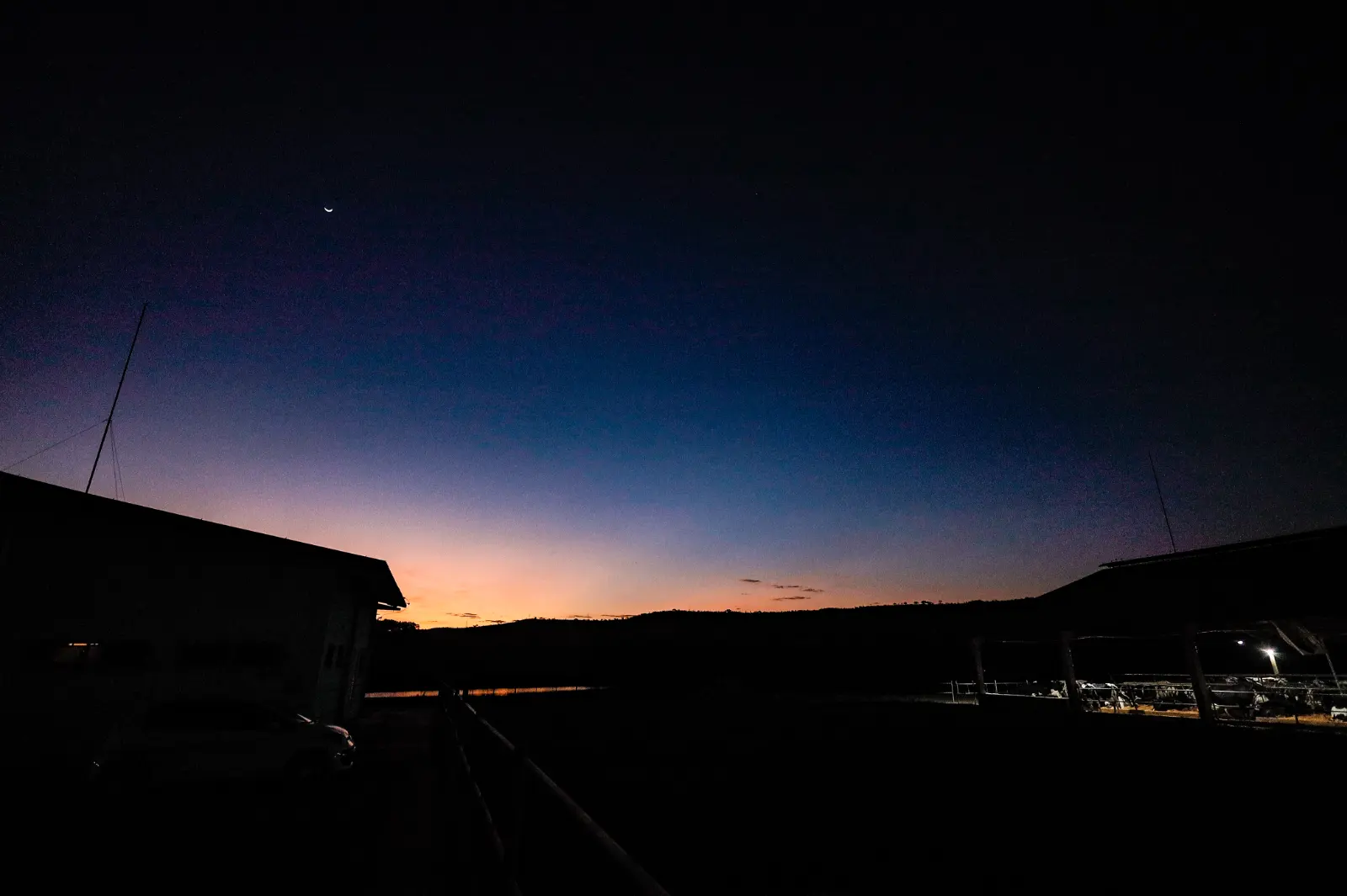 O último brilho do pôr do sol atrás do galpão, no fim do dia